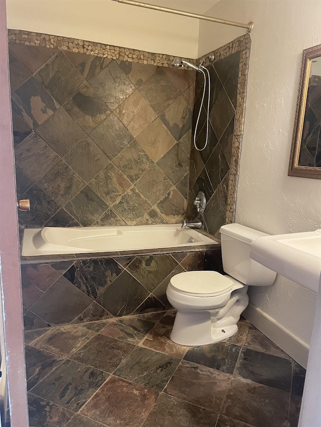 bathroom featuring tiled shower / bath combo and toilet