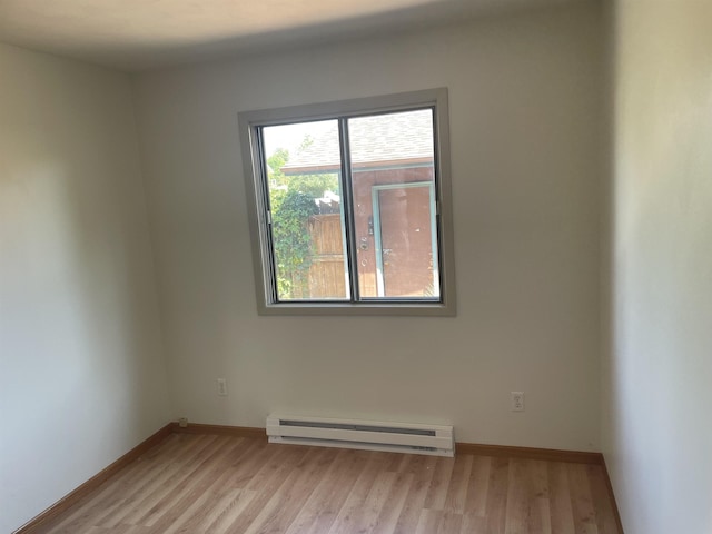 empty room featuring baseboard heating and light hardwood / wood-style flooring