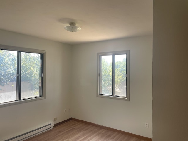 unfurnished room with a healthy amount of sunlight, light hardwood / wood-style floors, and baseboard heating