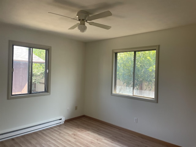 empty room with light wood-type flooring, plenty of natural light, a baseboard heating unit, and ceiling fan