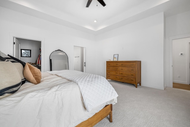 carpeted bedroom with a walk in closet, ceiling fan, and a closet