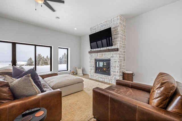 living room with ceiling fan, a stone fireplace, and hardwood / wood-style floors