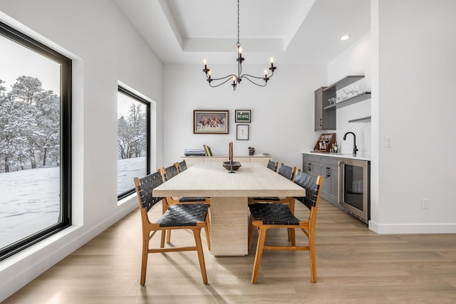 dining space featuring a chandelier, a tray ceiling, wine cooler, and a wealth of natural light