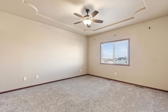 carpeted spare room featuring ceiling fan and a tray ceiling