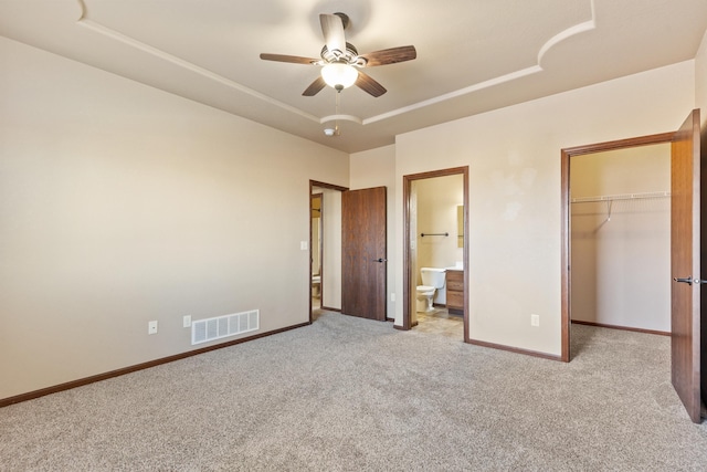 unfurnished bedroom featuring ceiling fan, light carpet, connected bathroom, and a closet