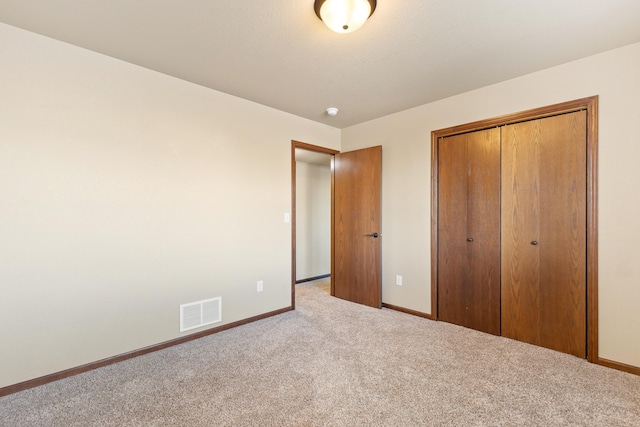 unfurnished bedroom featuring light colored carpet and a closet