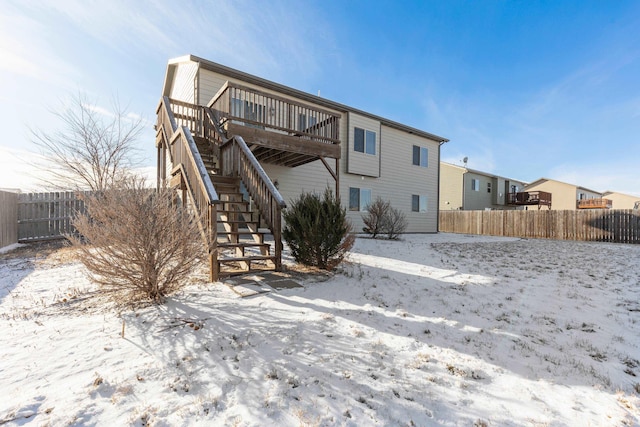 snow covered house featuring a wooden deck