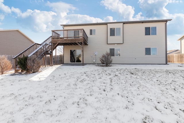 snow covered back of property featuring a deck