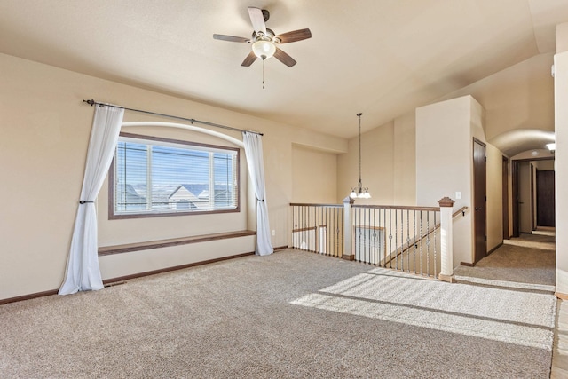 unfurnished room with ceiling fan with notable chandelier, light colored carpet, and vaulted ceiling