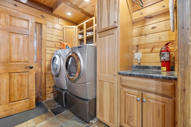 laundry area with washer and dryer, wood ceiling, cabinets, and wood walls