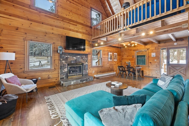 living room featuring beam ceiling, wood-type flooring, wooden ceiling, and a fireplace