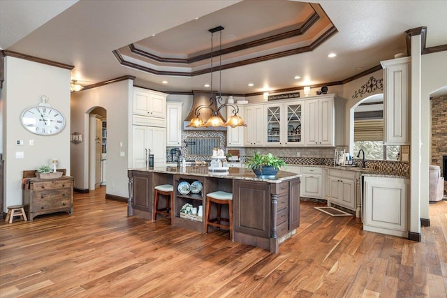 kitchen featuring a center island, white cabinets, ornamental molding, tasteful backsplash, and light stone counters