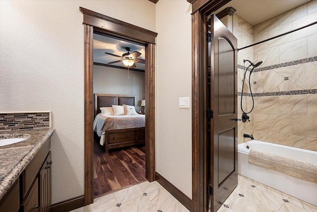 bathroom featuring decorative backsplash, ceiling fan, vanity, and tiled shower / bath