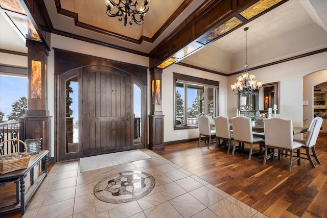 entryway featuring hardwood / wood-style flooring, an inviting chandelier, a tray ceiling, and ornamental molding