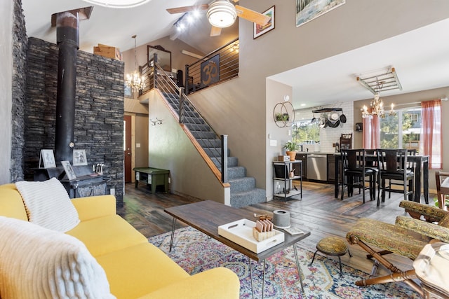 living room with wood-type flooring, ceiling fan with notable chandelier, high vaulted ceiling, and a wood stove