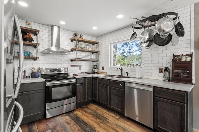 kitchen featuring appliances with stainless steel finishes, tasteful backsplash, dark wood-type flooring, sink, and wall chimney range hood