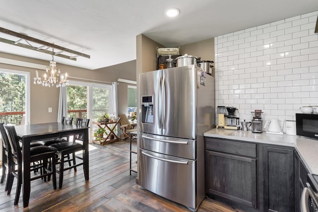 kitchen featuring pendant lighting, stove, dark wood-type flooring, an inviting chandelier, and stainless steel refrigerator with ice dispenser