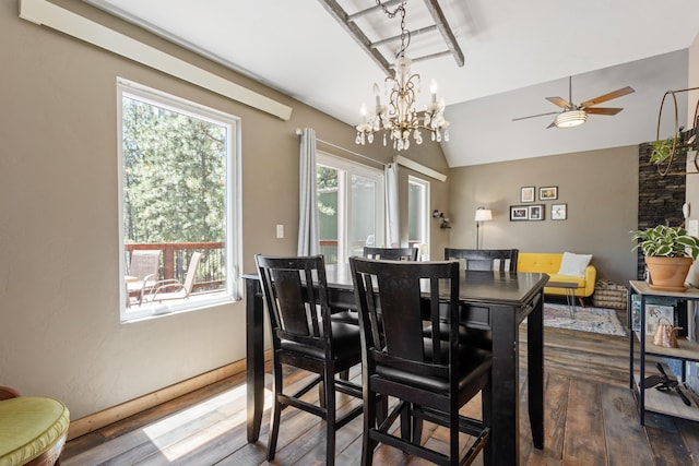 dining room featuring ceiling fan with notable chandelier, hardwood / wood-style flooring, and vaulted ceiling