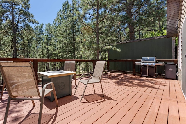 wooden deck with grilling area and an outdoor fire pit