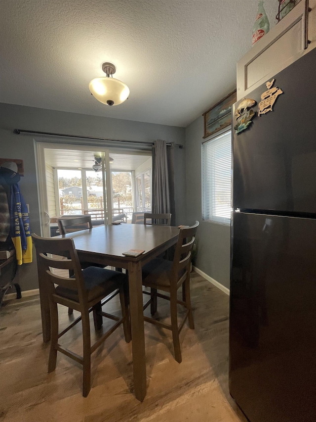 dining space with a wealth of natural light, a textured ceiling, and hardwood / wood-style flooring