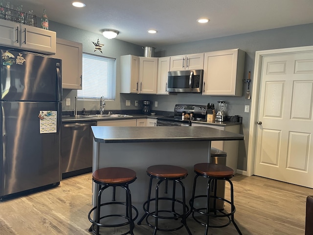 kitchen featuring white cabinets, sink, a kitchen island, a kitchen bar, and stainless steel appliances