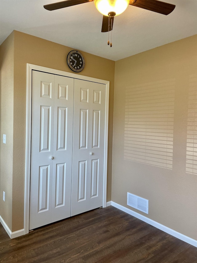 unfurnished bedroom featuring ceiling fan, dark hardwood / wood-style floors, and a closet