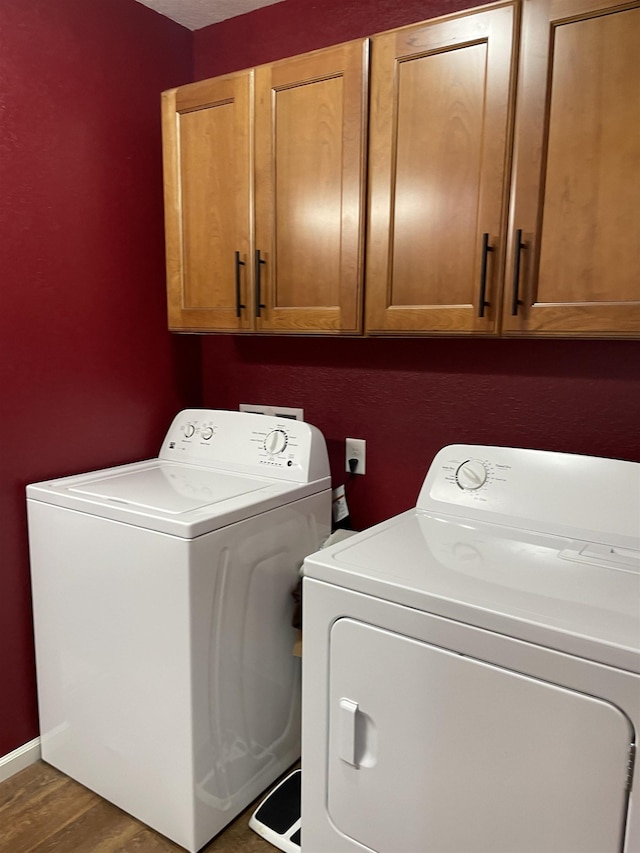 washroom with separate washer and dryer, cabinets, and dark hardwood / wood-style floors