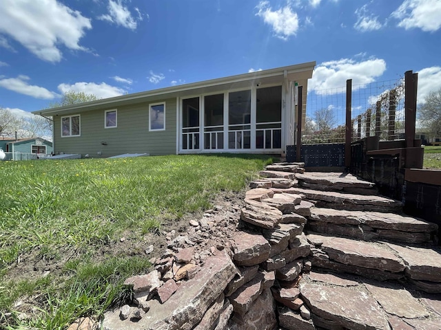 rear view of house featuring a sunroom and a lawn