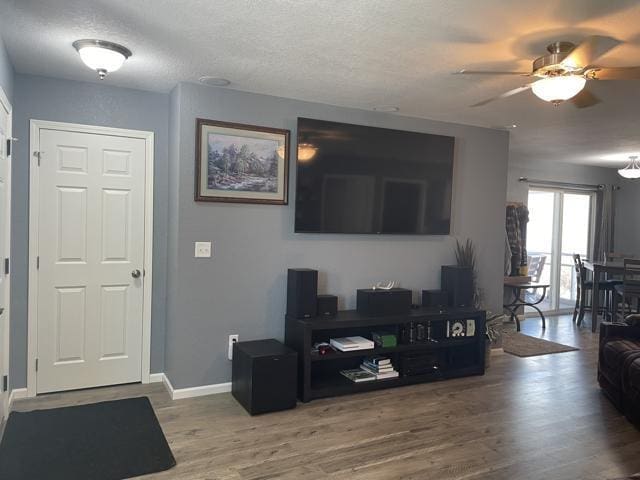 living room featuring ceiling fan, hardwood / wood-style floors, and a textured ceiling