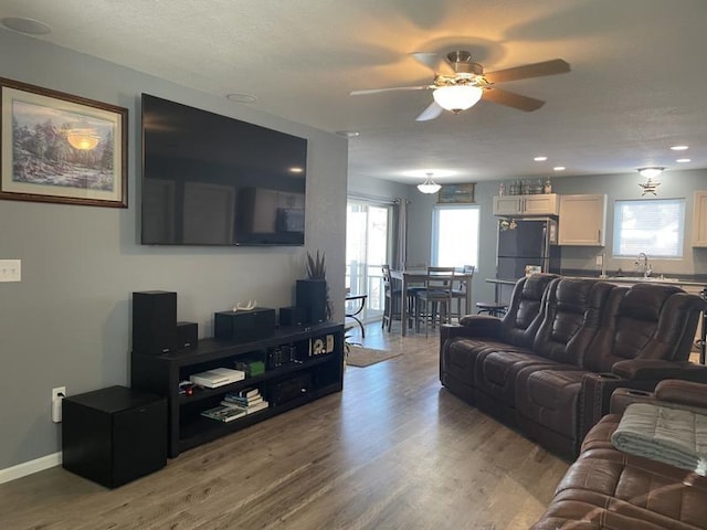 living room featuring hardwood / wood-style floors, ceiling fan, and sink