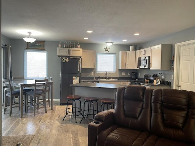 kitchen with light wood-type flooring, sink, a healthy amount of sunlight, and black appliances