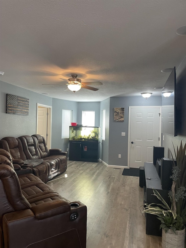 living room featuring ceiling fan, wood-type flooring, and a textured ceiling