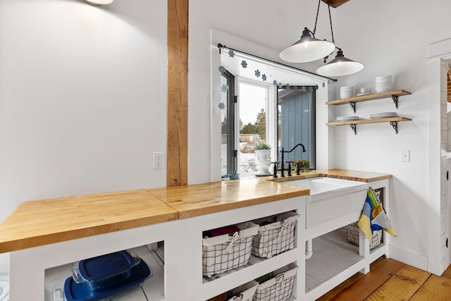 interior space featuring baseboards, wood counters, wood finished floors, decorative light fixtures, and open shelves