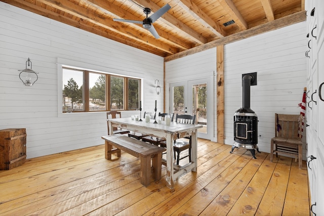 interior space with a wood stove, light wood-type flooring, wood ceiling, and beam ceiling