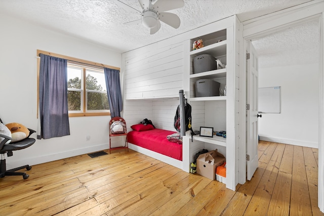 bedroom featuring a textured ceiling, visible vents, hardwood / wood-style flooring, and baseboards