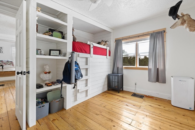 bedroom featuring wood-type flooring, ceiling fan, a textured ceiling, and baseboards