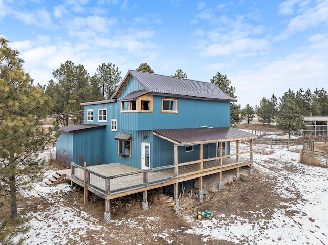 snow covered house with a deck and metal roof