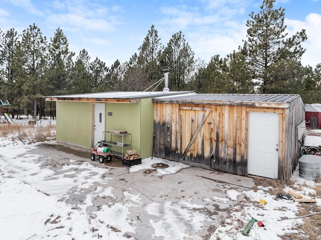 snow covered structure featuring an outbuilding