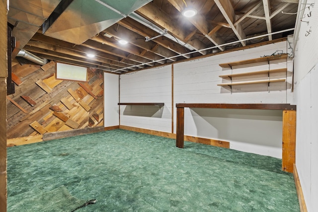 basement featuring wood walls and carpet