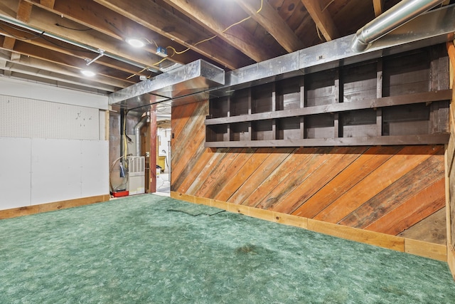 basement with carpet, wood walls, and heating unit