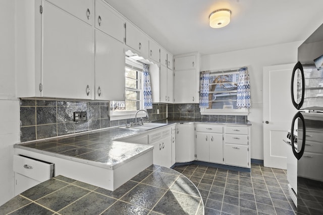 kitchen with tasteful backsplash, kitchen peninsula, white cabinetry, and sink