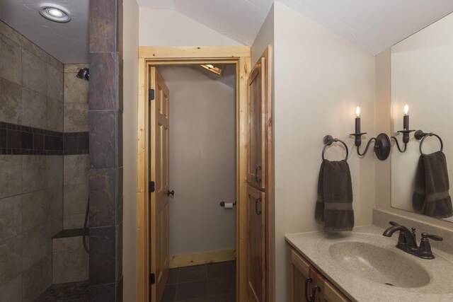 bathroom with tiled shower, tile patterned floors, vanity, and vaulted ceiling