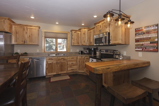 kitchen featuring light brown cabinets, sink, hanging light fixtures, kitchen peninsula, and stainless steel appliances