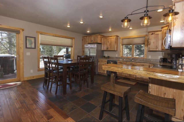 kitchen featuring pendant lighting, dishwasher, wood counters, sink, and stainless steel fridge