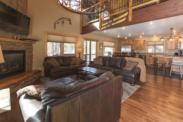 living room featuring a fireplace, a towering ceiling, light hardwood / wood-style floors, and a wealth of natural light