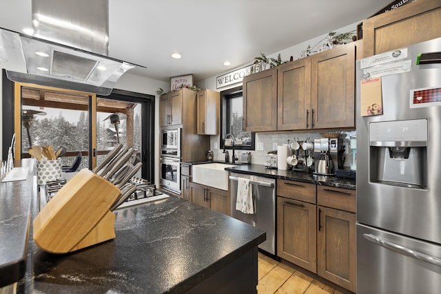 kitchen featuring stainless steel appliances, sink, light hardwood / wood-style flooring, decorative backsplash, and extractor fan