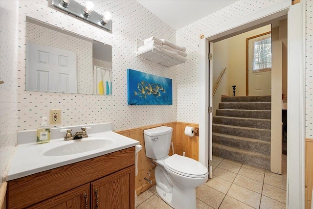 bathroom featuring tile patterned flooring, wooden walls, vanity, and toilet