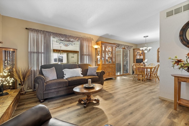 living room with a textured ceiling, hardwood / wood-style floors, and a notable chandelier