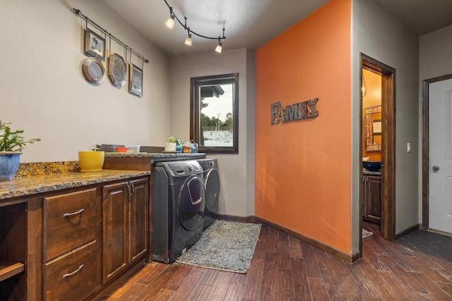 laundry area with dark wood-type flooring, cabinets, washing machine and clothes dryer, and track lighting