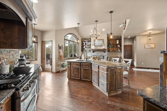 kitchen featuring a kitchen island, pendant lighting, a breakfast bar area, gas range, and a textured ceiling